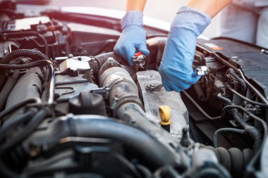 Bir araba servisinde tamirci olarak çalışan bir kadın İngiliz anahtarı kullanarak bir arabanın şasesini onarıyor. Konsantre kız bir araba tamirhanesinde ekipmanla araba tamir ediyor..