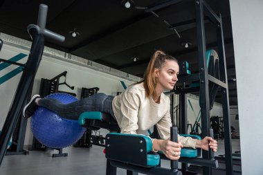 Çekici esmer kız vücudunu eğitmek için simülatör üzerinde egzersiz yapıyor. Crossfit ve güçlü kaldırma eğitimi. Spor. fitness konsepti.