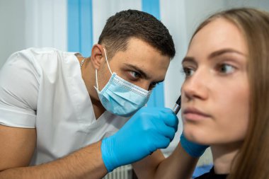 KBB doktoru otoskop kullanarak hastanın kulağını muayene ediyor. Odiyoloji. İşitme testi