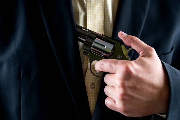 Businessman man in shirt and jacket with revolver isolated on black background. illegal business. a weapon in the hands of a bad person