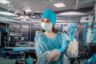 Ameliyathanede duran, tıbbi eldiven giyen güzel kadın doktor portresi. Modern bir ameliyathanede cerrah. İlaç. Ameliyathane