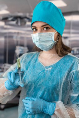 Kadın hemşire karmaşık bir ameliyat sırasında kauçuk lateks mavi eldiven giyer. Şırınga ellerinde. tıbbi çalışanlar