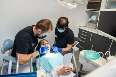 Güzel genç bir kız diş hekimliğine gelip ağız boşluğuna bakmış. Diş hekimliği konsepti. Dişçilik. dişçi ve yardımcı.