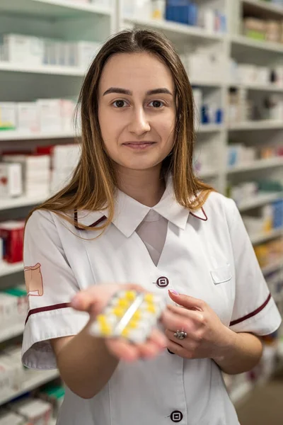 a beautiful young female pharmacist is waiting for visitors in a spacious pharmacy. Pharmacy concept. Portrait of a pharmacist