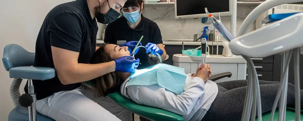 team of medical dentists in a dental office talking to a patient and preparing for treatment. treatment of the patient's teeth. brushing teeth