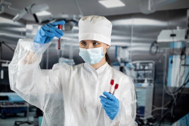 Kadın hemşire, bir kişinin test tüpünde kan testi yapar. İlaç. Hastanedeki kan örneklerini aldım. Test tüpündeki kan.