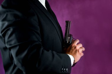 Siyah arka planda izole edilmiş bir suçlu olarak elinde silah tutan takım elbiseli adam. Silahlı adam kavramı. Nefsi müdafa