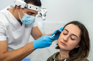 Doktorun randevusunda otoskop kullanan bir kadının kulağının gelişmiş muayenesi. Otoskopi. ENT doktorunu ve konsültasyonu ziyaret edin