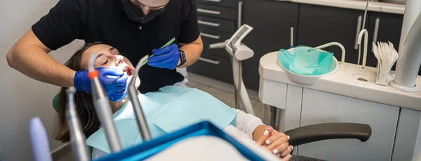 Pretty lady in the dentist's chair looking at her doctor close-up while the dentist is examining her teeth. the concept of examination of a patient with problems in the oral cavity