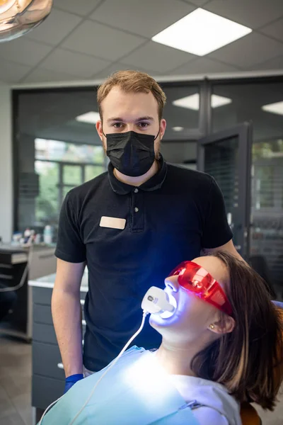 dentist with an assistant in overalls uses UV lamps during treatment of a patient\'s teeth. The concept of tooth restoration. dentist
