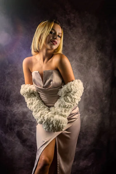 woman in a fur coat and a dress is photographed in a fashion studio isolated. of a beautiful sensual woman with white hair in a luxurious dress. portrait of a woman