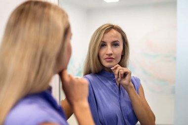Güzel, gülümseyen, neşeli, güzel saçlı, büyüleyici giyinmiş, mutlu bir şekilde kameraya bakan bir kadın. Stüdyo. Güzel bir kadın boş stüdyo duvarından izole edilmiş..