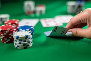Güzel genç bir kız elinde kartlarla poker masasında oturuyor. Şans pokeri. Kadınların elinde poker kartları var.