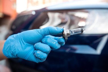 Güçlü bir tamircinin eli halojen araba lambalarını farlara dayar ve arabayı tamir eder. Güçlü bir tamirci tarafından araba tamiri.