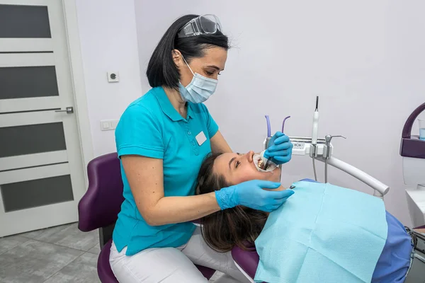 The orthodontist uses an intraoral scanner to scan the patient's teeth. The concept of a modern dental clinic with treatment.
