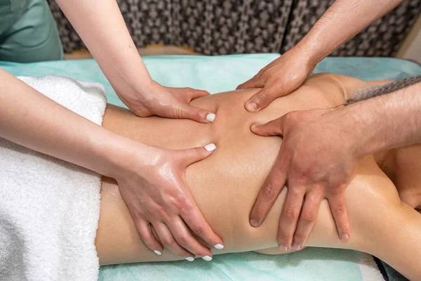 Massage in four hands over the patient\'s back is performed by two massage therapists, a woman and a man, at the same time. effective therapeutic massage. spa salon healthy body