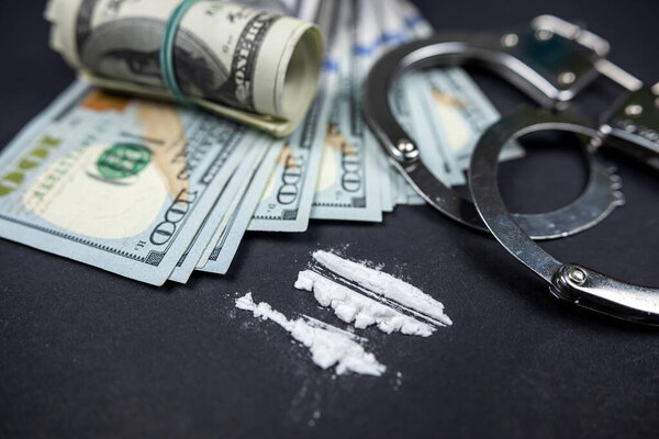 Plastic bags of cocaine or heroin and US dollar bills with handcuffs and bullets from a gun. violation of the law. Distribution of narcotics