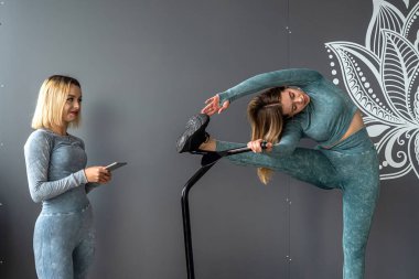 Güzel, genç bir kız antrenör spor salonundaki trambolinde nasıl antrenman yapılacağını gösteriyor. spor konsepti.