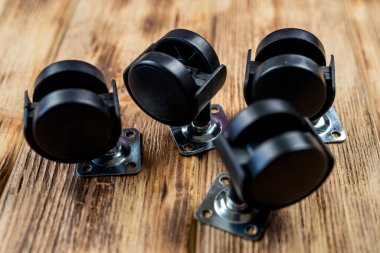 Bir ofis sandalyesi için mobilya çarkı ya da tekerlek masanın arka planına yerleştirilir. Yakın çekim görüntüsü. Mobilyalar için siyah tekerlekler