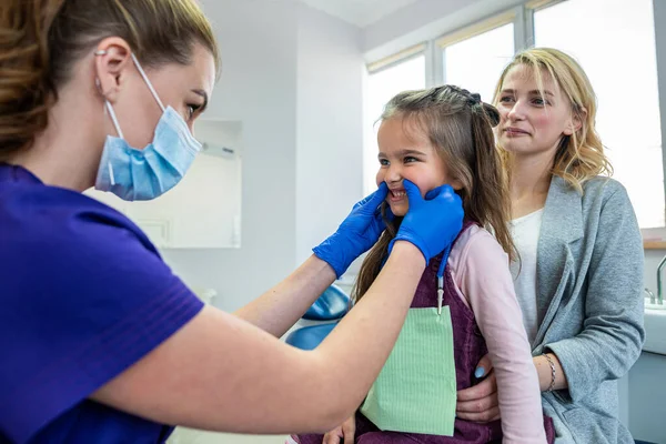 Mom and child  visit their pediatric dentist. Doctor talking with patient. Healthcare