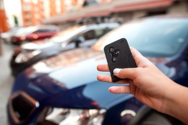 Parmaklıklı adam uzaktan kumanda tuşundaki siyah düğmeye basarak alarm sinyalini parlak araba alarmından uzaklaştırıyor. Arabanın anahtarlarıyla. Anahtarlar elindeyken arabayı açmak.