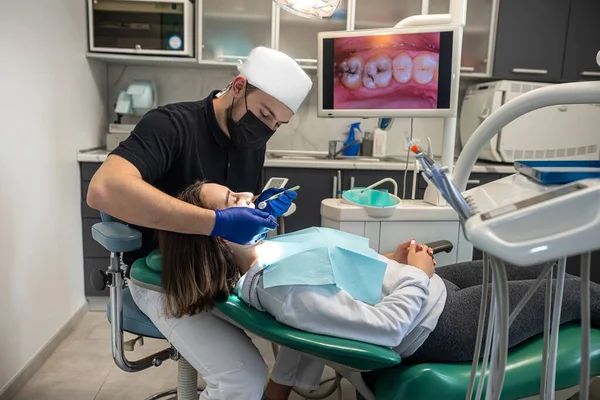 Pretty lady in the dentist\'s chair looking at her doctor close-up while the dentist is examining her teeth. the concept of examination of a patient with problems in the oral cavity