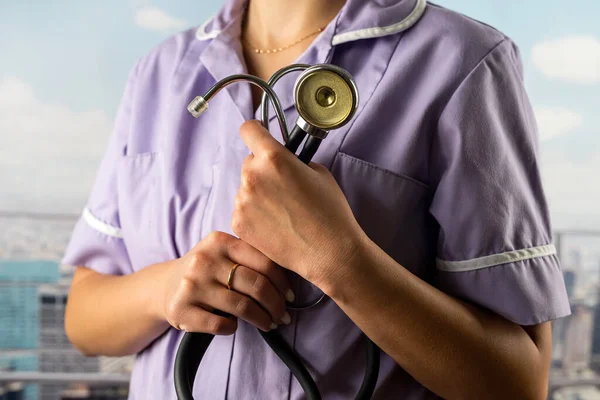 Portrait of a female doctor in a uniform with a stethoscope in her hands on the background of a hospital corridor. medicine. health care stethoscope in hands