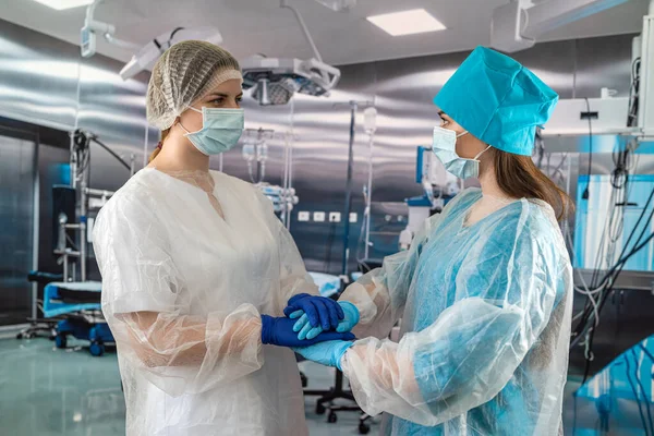 Two hospital employees a female surgeon and a nurse are standing with crossed arms in the hospital. Medical health care and doctor\'s service.