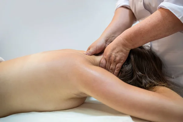 female client receiving physical therapy and treatment from female masseur on shoulders and back in beauty spa. spa treatments. back treatment body health