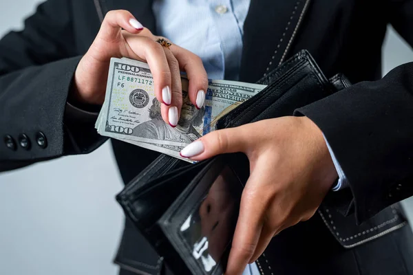 close-up of a female hand holding a black wallet in which there are dollars. woman with dollars money in wallet abundance