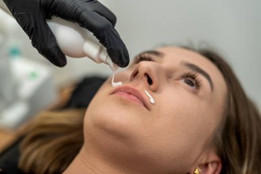 Üstat üst dudağının epilasyonundan sonra yatıştırıcı krem sürüyor. epilasyon kavramı