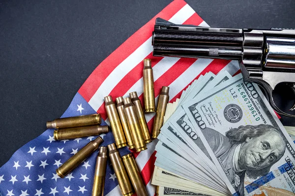 top view of a big black gun and a bunch of usa dollars on a big spacious usa flag. concept of weapons and money