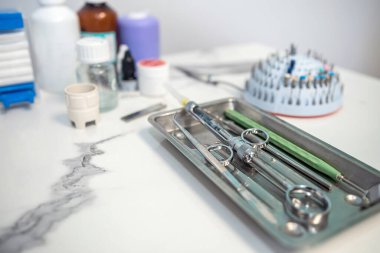 Dental tweezers lie in a metal tray and a bunch of other parts. dentistry