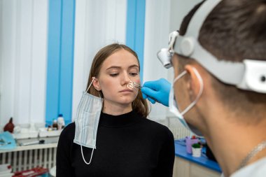 Burun sorunu olan bir kızla çalışırken bir otolaringolojistin portresi. İlaç. Burun sinüslerinin incelenmesi