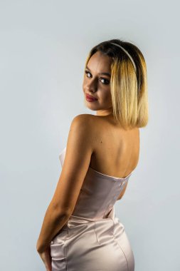 Beyaz saçlı zarif bayan stüdyo arka planında mutlu bir şekilde gülümsüyor. Narin beyaz ipek elbiseli bir model. Askılı, saten bir gece elbisesi giyen moda kadını. izole