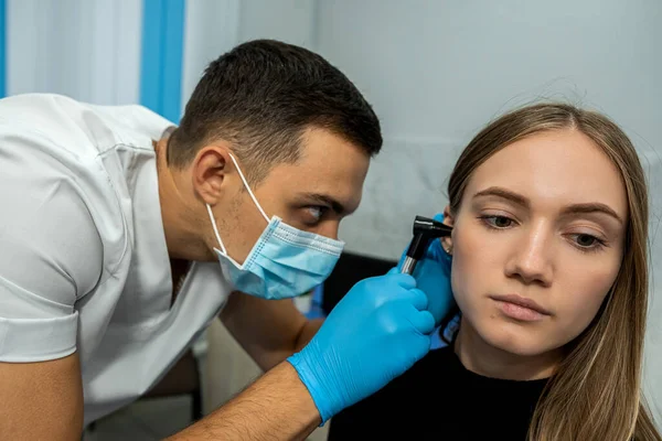 An otolaryngologist examines the auricle. Hearing clinic. An ENT doctor with instruments in a mask and gloves examines the patient's ear.