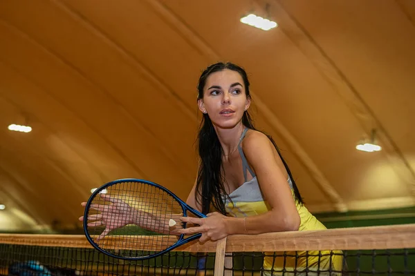 portrait of a joyful young woman in a short sports dress holding a tennis racket. sport. hobby court. tennis