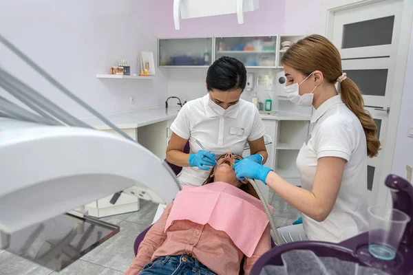 young female patient being examined and treated by a female dentist and an assistant in a dental clinic. treatment of the oral cavity