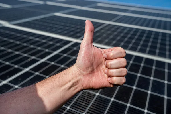 solar panel on the roof produces electricity on the background of a hand with a finger up. investment in saving electricity