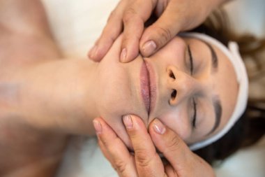 girl client is lying down for a facial massage in the best spa salon in town. close up face massage satisfied customer