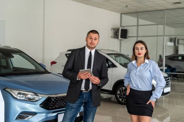 professional consultant provides all information about a new car using a tablet to his client at a car dealership