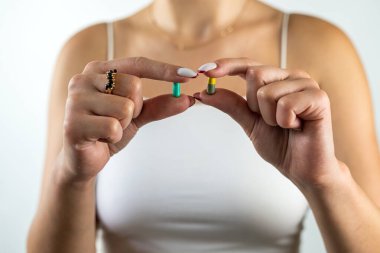 Yakın plan kadın mide ağrısı için bir hap alıyor ve ilaç istemek için bir bardak su tutuyor. Beyaz bir arka planda izole edilmiş. Tıp konsepti. Sağlık ve insan koruması.