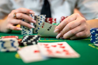 Young woman sitting at table playing poker and holding cards proudly celebrating victory and success and very excited. gambling woman playing poker. cropped photo. isolated