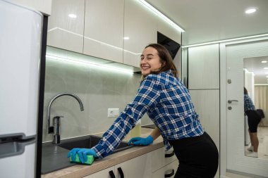 beautiful young woman is cleaning while smiling while doing this in a modern kitchen. cleaning is a joy. the woman cleans. clean house