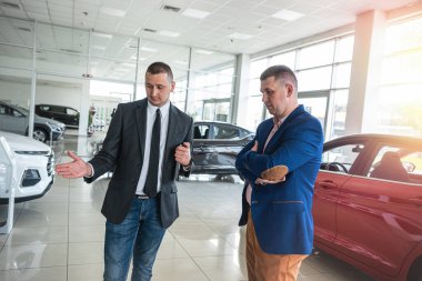 Galeride satın almadan önce yeni bir otomobil seçen ve inceleyen genç profesyonel yönetici ve erkek müşteri