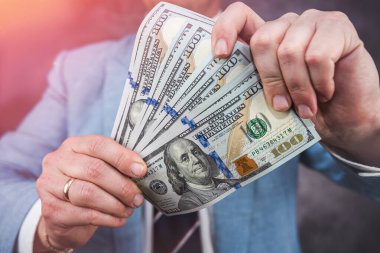 close up of 100 one hundred dollars bills in a man's hand. money concept