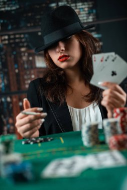 Female hand with playing cards and poker chips and burning cigar close-up in front of poker table. poker concept. game for money