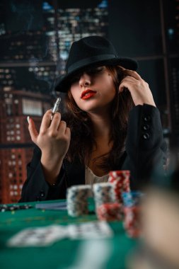 image of a young sexy woman playing poker with a cigarette and smoke coming out of it. poker in the casino. woman with cards
