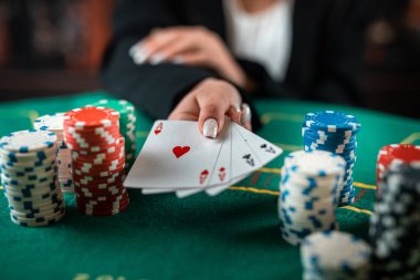 female hand takes poker chips from a pile at a round poker table. risky bets in poker. a woman plays a man's game. woman's hands