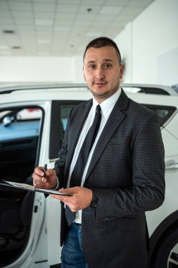 Smiling businessman choosing best modern car at showroom. sale or rent auto concept